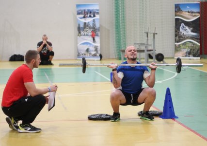 Podnoszenie sztangi przez zawodnika obserwuje sędzia