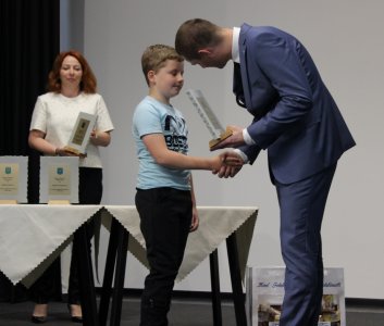 Przewodniczący Janusz Podżorski przekazuje statuetkę Tymoteuszowi Szalbotowi