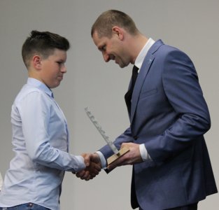 Przewodniczący Janusz Podżorski przekazuje statuetkę Tomaszowi Wąsowiczowi